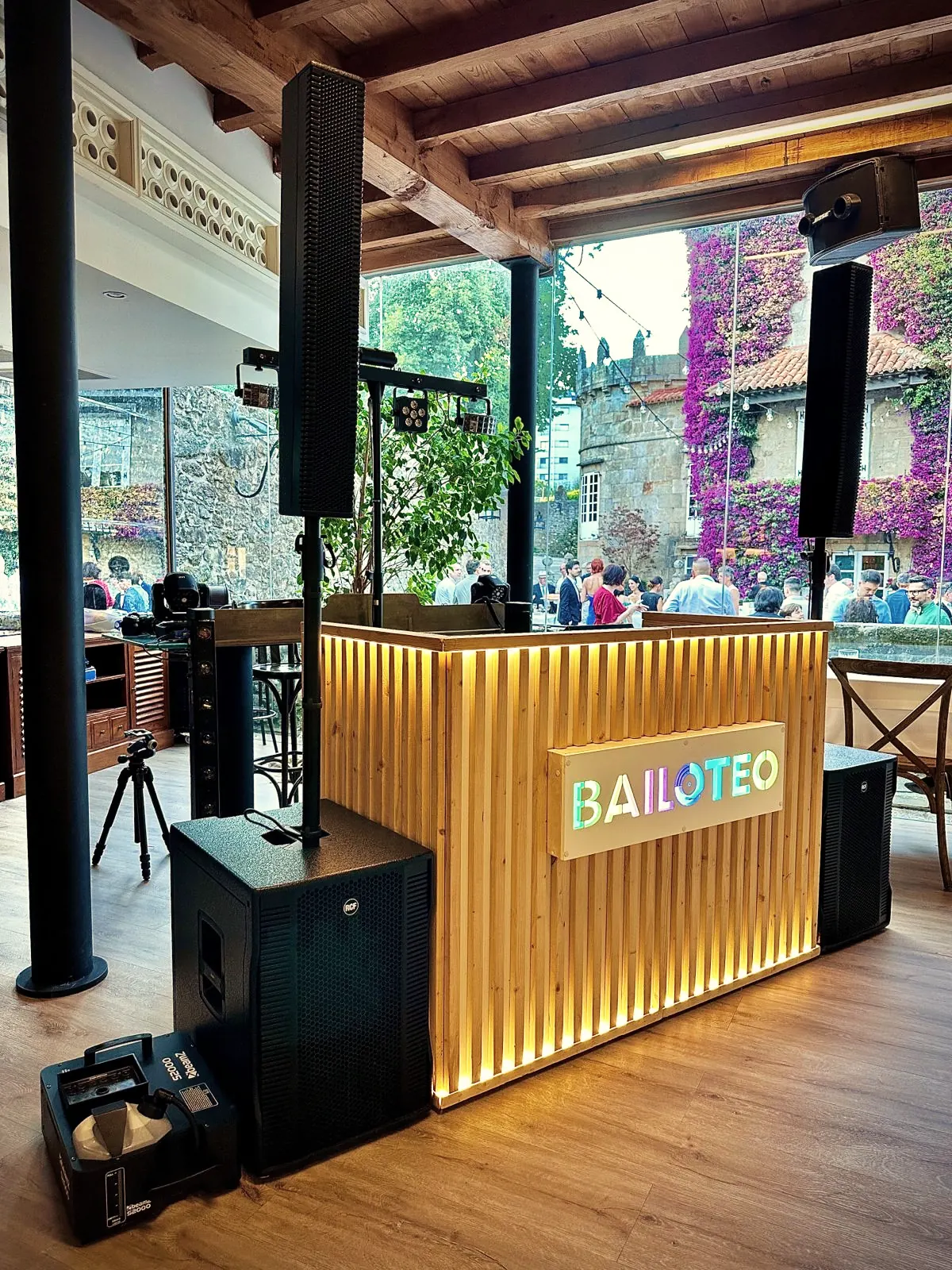 Cabina DJ de lamas de madera clara con luz LED cálida y logo de Bailoteo