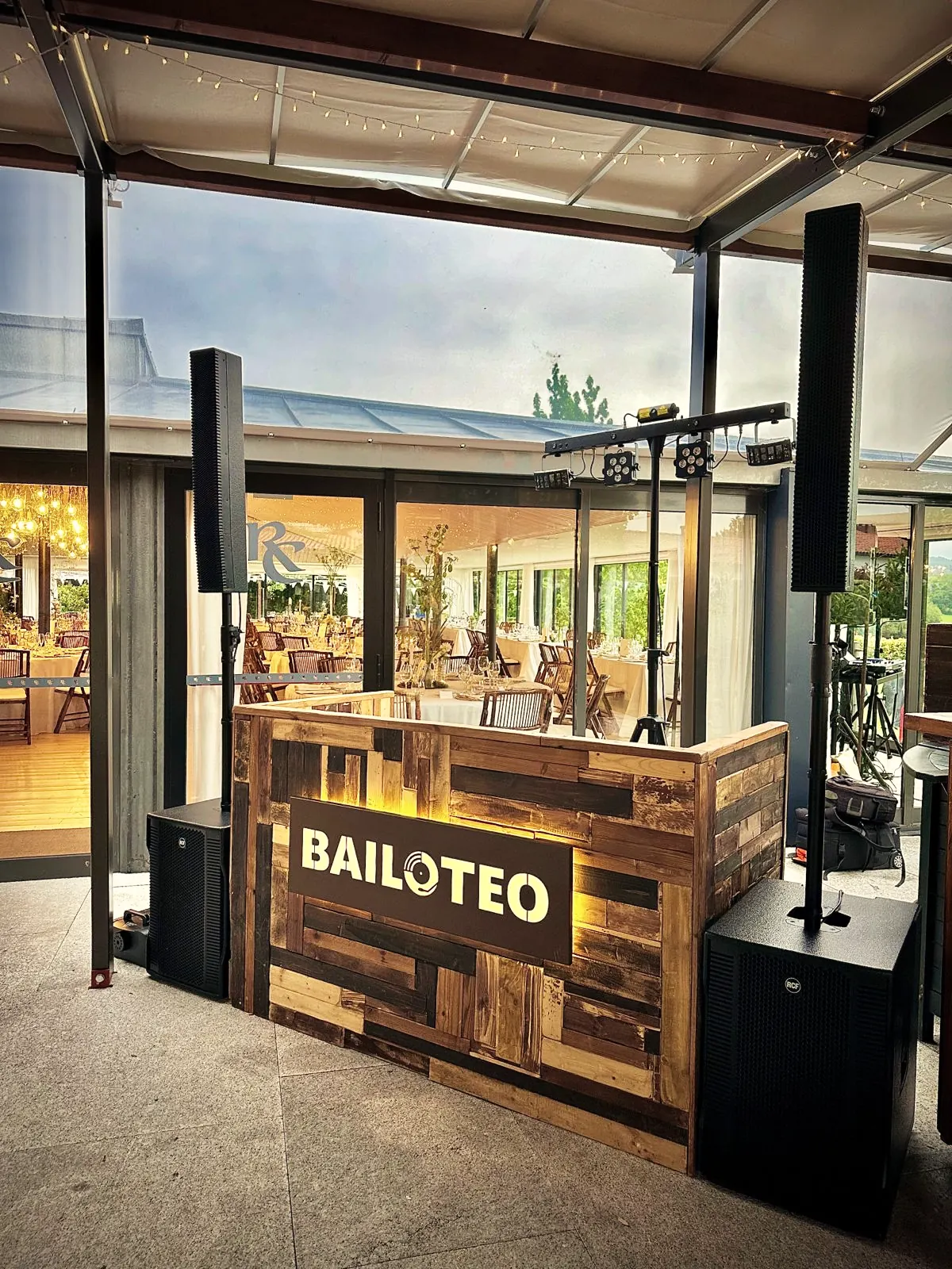 Cabina DJ rústica de madera recuperada con el logo de Bailoteo retroiluminado