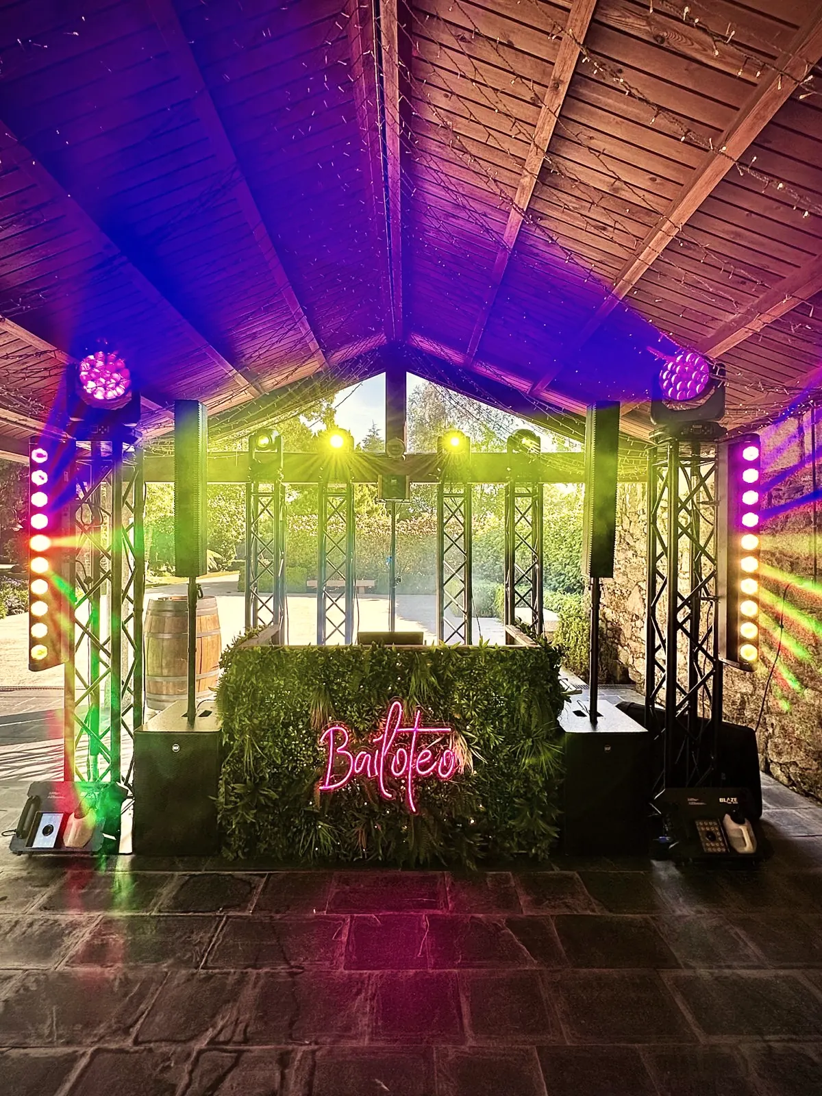 Iluminación para bodas con estructura truss, cabezas móviles y barras LED alrededor de la cabina DJ