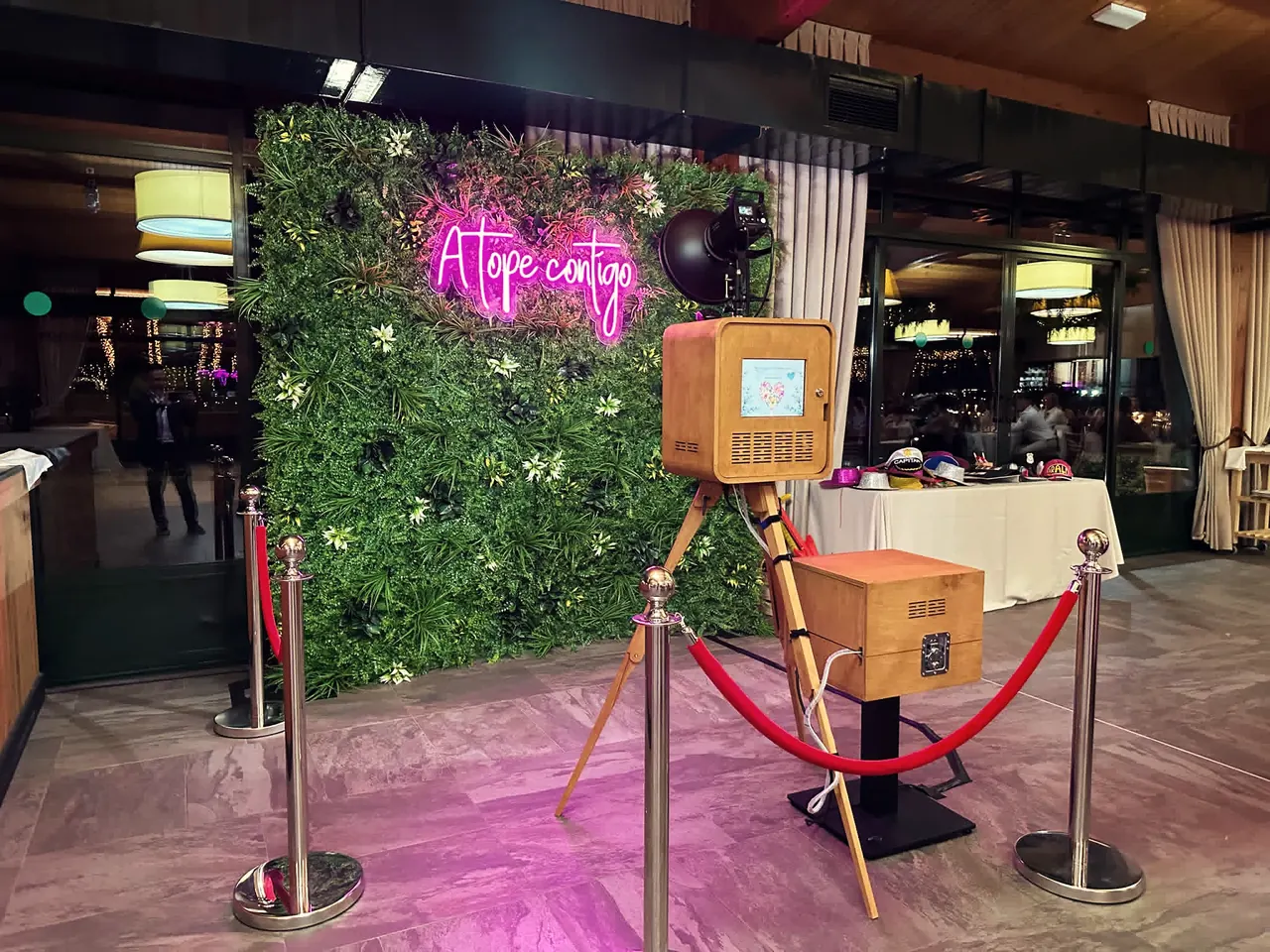 Fotomatón retro de madera con neón «A tope contigo», pared vegetal y cordones rojos