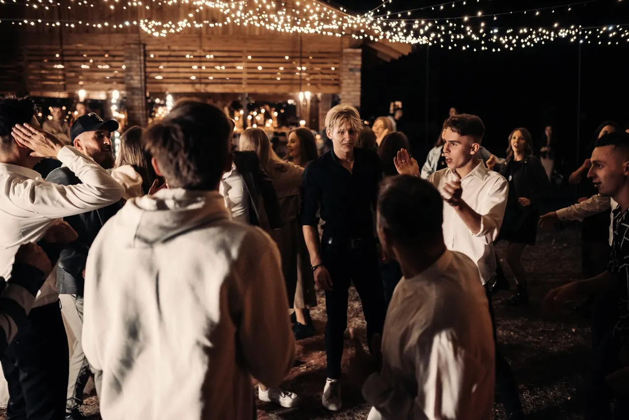 Invitados bailando de noche bajo guirnaldas de luces en una fiesta al aire libre